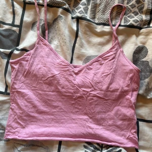 Ljusrosa linnetopp med smala axelband - Söt ljusrosa linnetopp med smala axelband och v-ringad halsringning. Toppen är ärmlös och har en enkel, stilren design som passar perfekt till sommaren. Tillverkad i mjuk bomull för en skön känsla. Kort i längden.