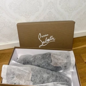 Christian Louboutin svarta sneakers - Säljer ett par svarta sneakers från Christian Louboutin med ikonisk röd sula och snygg snörning. Skorna har en stilren design i mocka och skinn, med diskreta detaljer och klassisk rund tå. Perfekta för dig som vill sticka ut med exklusiv känsla.