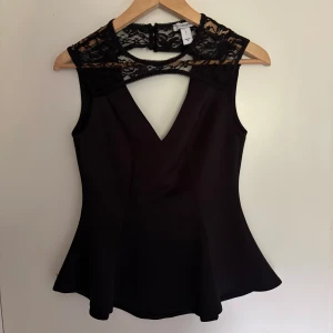 Svart spetsblus - Supersnygg svart blus från Oneness med v-ringning och spets upptill. Har ett litet hål i spetsen på baksidan av ena axeln