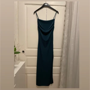Mörkgrön långklänning med slits -  Mörkgrön festklänning från Misty Rose – använd vid Homecoming & bal Säljer denna eleganta klänning som jag köpte i Kalifornien inför min Homecoming-dans. Jag har bara använt den två gånger: en gång där och en gång på balen i Sverige. Den är i nästan nyskick – inga fläckar, hål eller slitage.  • Färg: Djup mörkgrön • Passform: Stretchigt tyg som sitter tight och följsamt mot kroppen • Design: Tunna axelband, hög slits, figurnära siluett • Storlek: Jag har storlek Small (EU 36) och den passar m