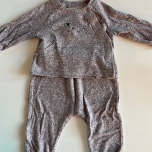 Grå tröja och byxor från mywearbaby - Mysig grå tröja och byxor från mywearbaby i storlek 68. Tröjan har lång ärm, knappar på axeln och ett broderat motiv framtill. Perfekt för kyliga dagar. 