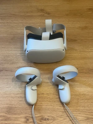 Oculus Quest 2 VR-headset med kontroller - Säljer ett Oculus Quest 2 VR-headset i vit plast med matchande kontroller. Headsetet har justerbart band och mjuk vaddering för komfort. Kontrollerna har handledsremmar och ergonomisk design för smidig gaming. Perfekt för dig som vill uppleva VR-spel på riktigt. Kom med pris förslag!