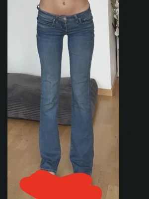 Blå bootcut jeans från LTB - Snygga blå jeans från LTB med bootcut-modell och låg midja. Jeansen har klassiska bakfickor med dekorativa sömmar och en stilren look. Perfekta för dig som gillar en tidlös och trendig stil. 24/34