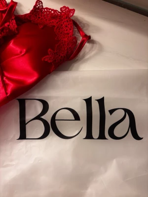 Rött satin nattlinne från Bella - Rött nattlinne i glansigt satinmaterial med spetsdetaljer vid byst och axelband. Linnet är lite längre än ett vanligt linne,  Den är helt ny så jag skickar i förpackningen den kom i. PS! Jag skickar posten om du köper innan kl 17🥰