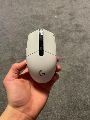 Logitech G305 trådlös gamingmus vit - Säljer en vit Logitech G305 trådlös gamingmus med svart scrollhjul och diskret blå logotyp undertill. Musen har en ergonomisk form, flera knappar och är tillverkad i plast. Perfekt för gaming eller arbete vid datorn.