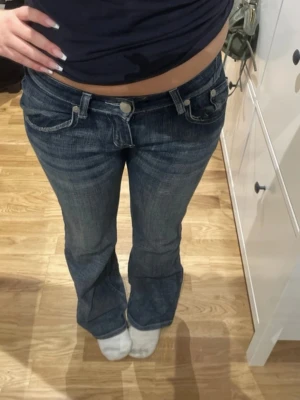 Victoria Beckham blå bootcut jeans - Mörkblå bootcut jeans från Victoria Beckham med låg midja och broderade kronor på bakfickorna. Är 163 och byxorna är i strl 29