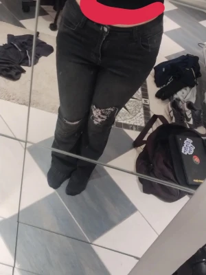 Svarta bootcut jeans med slitningar - Säljer ett par svarta bootcut jeans med slitningar och hål på ena knät. 