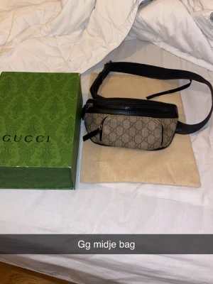  axelväska med GG-mönster - Snygg axelväska f med klassiskt GG-mönster i beige och brunt, svarta skinn-detaljer och justerbart band. Perfekt för att bära det viktigaste med stil. Levereras med originalbox och dustbag.