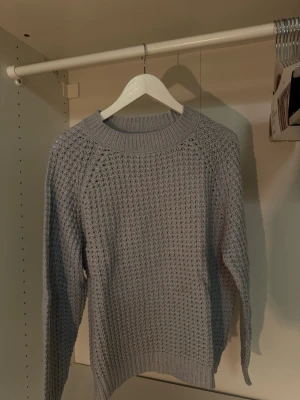 Ljusblå stickad tröja från 157 - Säljer en ljusblå stickad tröja från 157 med grovstickat mönster och rund hals. Tröjan har långa ärmar och bred ribbstickad kant vid hals, ärmslut och nederkant. Perfekt för kalla dagar och enkel att matcha med olika outfits. Obs en skugga på första bilden, inte en fläck💙🤍