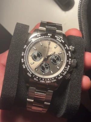 Seiko kronograf herrklocka silver - Stilren Seiko kronograf med silverfärgad urtavla och svarta detaljer. Klockan har tre subdials, svart bezel och ett robust länkarmband i rostfritt stål. Perfekt accessoar för dig som gillar sportig och klassisk stil.