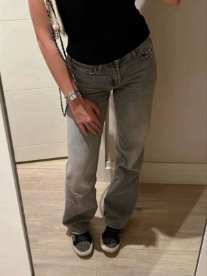 Gråa bootcut jeans - Säljer ett par bootcut gråa jeans i ny skick. Jeansen har klassisk femficksdesign och är tillverkade i bomull. Perfekta för en avslappnad och trendig look.