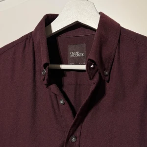 Oscar Jacobson Skjorta - Väldigt fin Oscar Jacobson ”Flanell” Skjorta i en vinröd färg i strl S, sitter som S-M, skick: 9-10, väldigt fräsch! Sista bild visar en missfärgning under armhåla, syns ej när man har på sig skjortan. Köpt på Volt för 1299 kr! 