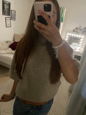 Beige stickad kortärmad tröja - Mysig beige stickad tröja med korta ärmar och hög hals. Tröjan har en avslappnad passform och är perfekt att matcha med jeans för en chill look. Materialet ser ut att vara mjukt och lite luddigt, vilket ger en skön känsla. Den är i storlek M men den passar S. Köpte den i oktober och har andvänd 7-9 gånger den är väldigt varm och snygg . Kontakta om frågor , innan köp och fler bilder ❤️