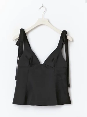 Svart satinlinnetopp med knytband från gina tricot - Stilren svart linnetopp i satin med djup v-ringning och breda axelband som knyts upptill. Toppen har en figurnära passform och är perfekt att styla med jeans eller kjol för en trendig look. helt slutsåld. helt ny med prislapp kvar, den var för liten.