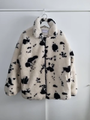 Cow print teddyjacka S ASOS DESIGN - Mysig teddyjacka från ASOS DESIGN i vit färg med svarta fläckar. Jackan har hög krage, dragkedja framtill och två sidofickor. Materialet är fluffigt och känns riktigt mjukt, perfekt för kyliga dagar. Snygg och trendig modell som sticker ut. Fint skick, storlek S men oversize, passar som M/L.