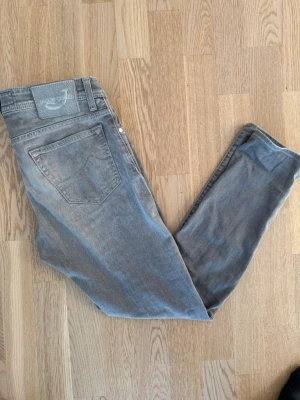 Grå jeans från Jacob Cohen - Snygga grå jeans från Jacob Cohen med klassisk femficksdesign och diskret logga på bakfickan. Jeansen har raka ben och är tillverkade i mjuk bomullsdenim som ger en skön känsla. Perfekta för dig som gillar stilrena och tidlösa plagg, notera liiiten slitning vid fickan , behövs en tvätt annars flawless. Size 31, modell 688 c. För frågor kom pm, allt gott / Neo