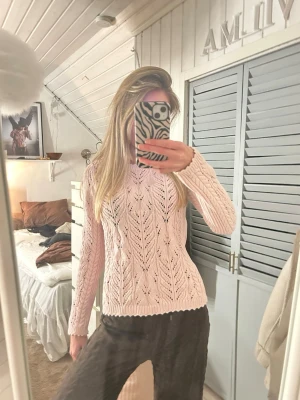 Ljusrosa stickad tröja med hålmönster - Supersöt ljusrosa stickad tröja med hålmönster och rund hals. Tröjan har långa ärmar och ribbade muddar vid ärmslut och nederkant. Perfekt för lager-på-lager och ger en mjuk, feminin look. Står ingen storlek men passar mig som annars har xs/s