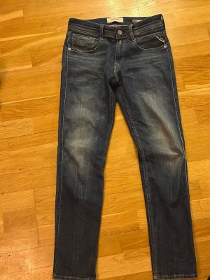 Blå Replay jeans slim fit - Snygga blå jeans från Replay med klassisk femficksmodell och raka ben. Jeansen har diskreta slitningar och Replay-logga vid myntfickan. Perfekta till vardagslooken och tillverkade i mjukt denimtyg för skön passform. Längd 30. Bara höra av dig vid funderingar 