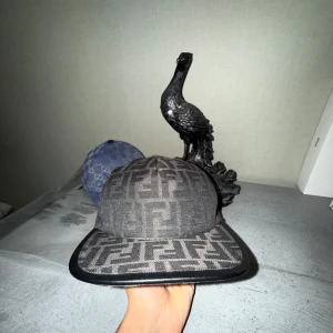 Fendi keps med FF-mönster - Säljer en snygg keps från Fendi i mörkgrått med det klassiska FF-logomönstret över hela kepsen. Kom med bud. Insta: TrendCollectiv. Fraktas och möts, Göteborg.