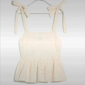 Vit broderad linnetopp från Madewell - Supersöt vit linnetopp från Madewell med broderade detaljer och volang nertill. Toppen har knytband på axlarna och är ärmlös, perfekt för en somrig look. Tillverkad i bomull och har en luftig, lätt känsla. Säljs i storlek XXS. Nypris ca 1000kr