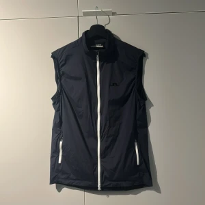 J. Lindberg vindväst - J.Lindberg väst i nyskick. Mörkblå och inga defekter alls. Nypriset ligger runt 1500! Hör av er vid minsta fundering!!