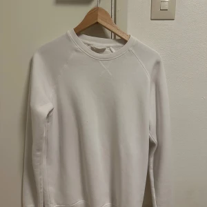 Vit sweatshirt från Pier One - Klassisk vit sweatshirt från Pier One med rund halsringning och ribbade muddar. Tröjan har en enkel och clean design, perfekt för en chill och stilren look. Tillverkad i mjuk bomull för maximal komfort. Långärmad modell som passar året runt.