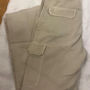 Beiga och khakigröna cargopants från Zara - Två par cargopants från Zara, ett par i beige och ett i khakigrönt. Båda har stora fickor på benen och bakfickor med lock. Tillverkade i bomull med normal passform och raka ben. Perfekta för en avslappnad och trendig look. Dom gröna är storlek 42 men passar även till 44 väldigt oversize 🌸