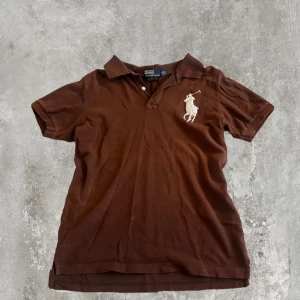 Brun Polo t-shirt från Ralph Lauren - Brun t-shirt från Polo Ralph Lauren med klassisk krage och korta ärmar. Strl S-M, dm för fler frågor 