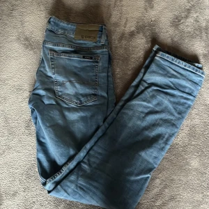 Blå slim fit jeans från Garcia - Snygga ljusblå jeans från Garcia med slim fit och midwaist. Klassisk femficksmodell med dragkedjegylf för en cool look. Perfekta för dig som gillar en slim passform och vill ha ett par stilrena jeans i garderoben. Mycket bra skick.