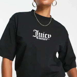 Svart t-shirt Juicy Couture - Svart t-shirt från Juicy Couture med vit logga tryckt på bröstet. Klassisk rund halsringning och korta ärmar. T-shirten har en loose passform och är tillverkad i mjuk bomull för en skön känsla.