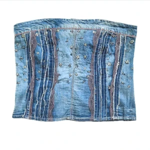 Jeans topp   - Passar som topp för mig som vanligtvis bär 36/S Unik tubtopp i denim med broderade små blommor och lila spetsdetaljer. Toppen har bandeau-modell och smockad rygg för skön passform. Snygga råa sömmar och dekorativa detaljer ger en cool vintage vibe. Perfekt att styla till både jeans och kjol.