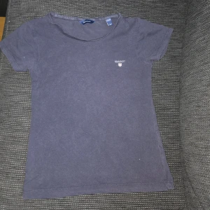 Mörkblå t-shirt från GANT - Snygg mörkblå t-shirt från GANT med klassisk logga broderad på bröstet. T-shirten har rund halsringning och korta ärmar. Tillverkad i mjuk bomull som är skön att ha på sig hela dagen.