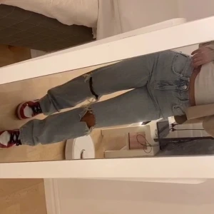 Ljusblå ripped jeans med raka ben - Säljer ett par ljusblå jeans med raka ben och slitna detaljer vid knäna. Jeansen har klassisk femficksdesign, hög midja och är tillverkade i denim. Perfekta för en avslappnad och trendig look.  Aldrig använda med prislapp på. Nypris: 599kr