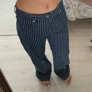 Randiga baggy jeans från Bershka - Säljer ett par mörkblå baggy jeans från Bershka med vita vertikala ränder. Byxorna har klassisk femficksmodell, hällor för bälte och knappstängning. Snygg loose baggy fit och riktigt sköna att bära till vardags. Finns två små fläckar som inte märks om man inte kollar efter dem.