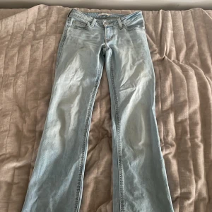Levi's Superlow Bootcut ljusblå jeans - Säljer ett par Levi's Superlow Bootcut jeans i ljusblå . Klassisk femficksmodell med låg midja och bootcut-ben. Jeansen har Levi's ikoniska läderpatch bak och röda logotagg på fickan. Perfekta för dig som gillar retrovibbar och snygg passform. Storlek 23 i midjan och 32 i längden.   250 kr+ frakt.