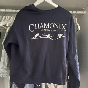 Mörkblå Chamonix sweatshirt - Mörkblå sweatshirt med broderad vit text 'Chamonix The French Alps' och skidåkare framtill. Klassisk rund halsringning och långa ärmar. Perfekt för dig som gillar alpstilen och vill ha en skön tröja med sportig vibe.
