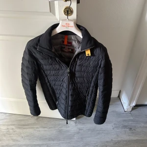 Svart pufferjacka Parajumpers XS - Svart pufferjacka från Parajumpers i storlek XS. Jackan har quiltad design, dragkedja framtill och en gul detalj vid kragen. Super lightweight-modell som är perfekt för kyliga dagar. Snygg passform och klassisk look med långärmade ärmar. Och som ni ser på sista bilden är de ett litet hål men inget som jag har tänkt på innan. Inget man märker. Bara att skriva om ni har nån fråga 😁 