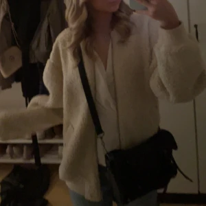 Beige teddyjacka från Lindex - Supermjuk och oversized teddyjacka från Lindex i beige. Jackan har dragkedja framtill, ribbade muddar och två fickor. Perfekt för dig som vill ha en mysig och trendig look. Passar till jeans eller kjol för en chill vibe.