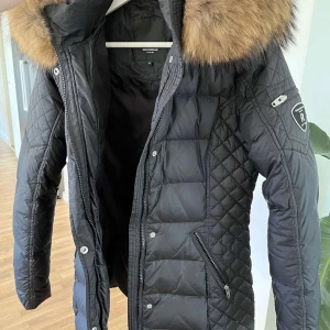 Svart dunjacka med päls från rock and blue - Jättefin svart dunjacka från Rockandblue med stor fluffig päls. Använd 2-3 gånger därav ser den ut som ny. Pris kan diskuteras