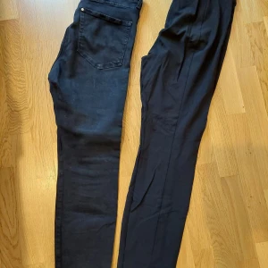 Svarta skinny jeans & kostymbyxor L - Två par svarta byxor i storlek L. Ena paret är H&M True To You skinny jeans i stretchigt denim med klassiska fickor och smal passform. Det andra paret är svarta kostymbyxor med pressveck och diskreta fickor, perfekt för en clean look.