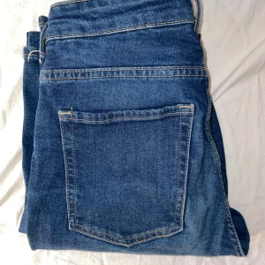 Blå bootcut jeans  - Snygga blå jeans i klassisk modell med fem fickor och silverfärgade nitar. Tillverkade i slitstarkt denimtyg. Perfekta för dig som gillar en tidlös och enkel stil. Bootcut och high waist