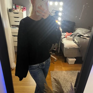 Svart stickad tröja med vida ärmar - Mysig svart stickad tröja med rund hals och extra vida, långa ärmar. Perfekt för kyliga dagar och enkel att matcha med jeans eller kjol. Tröjan har en loose fit och är superbekväm att bära.