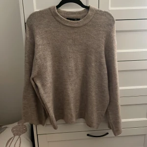 Beige stickad tröja från 157 - Mysig beige stickad tröja från 157 med rund halsringning och ribbade muddar. Perfekt för lager-på-lager och chill dagar. Långärmad och i en klassisk, enkel modell som funkar till allt.