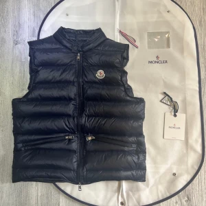 Moncler väst gui - Hejsan jag säljer nu min mörk blåa moncler väst som är i jättebra skick, jag har inte andvänt den så mycket kanske 2/3 gånger jag säljer den pågrund av att den inte passade min stil, den är köpt ifrån Nk Göteborg och kvittot finns, Priset är hugget i Sten, hör av dig vid minsta lilla fråga!🙌