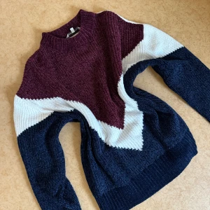 Stickad tröja i vinrött, vitt och marinblått - Säljer en stickad tröja med coolt färgblocksmönster i vinrött, vitt och marinblått. Den är i large storlek men passar bra som en oversized sweatshirt om du när på S/M som mig ☺️Tröjan har lång ärm, högre ribbad hals och är riktigt mjuk och chunky. 
