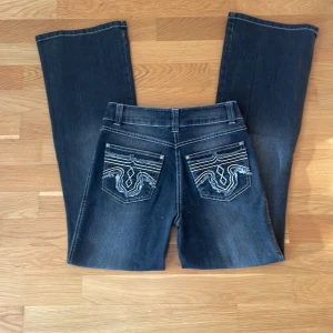 Svarta Jeans   - Svarta/mörkgråa jeans med utsvängda ben och coola broderade bakfickor med fransade detaljer. Jeansen har vita kontrastsömmar. Lite osäker på vilken storlek det är men upplevs som 36. 💞