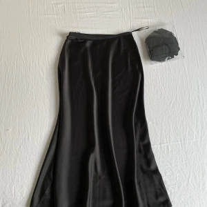 Helt ny Svart satinkjol från Uniqlo XS - Supersnygg svart långkjol i satin från Uniqlo. Kjolen har en lätt glansig finish, elastisk midja. Perfekt för dig som gillar en stilren och enkel look med lite extra flow i tyget.