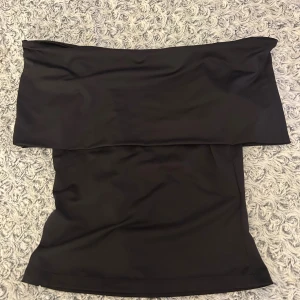 Svart tight topp från H&M XS - Enkel och stilren svart tight topp från H&M i storlek XS. Toppen har en rak och kroppsnära passform med bred linning upptill. Perfekt att matcha med en snygg kjol eller ett par nice jeans.