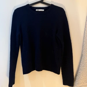 Mörkblå stickad tröja från Zara - Mysig mörkblå stickad tröja från Zara med rund hals och långa ärmar. Tröjan har ribbade muddar vid ärmslut och nederkant, vilket ger en snygg och enkel look. Ganska nopprig 