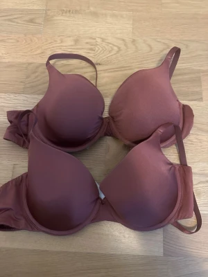 Brun vadderad bh med bygel - Två stycken bruna bh:ar  med vadderade kupor och bygel. Bh:arna har justerbara axelband och klassisk knäppning bak. Snygg, enkel design i mjukt och lent material. Välanvända, det enda anmärkningsbara är att kanten bh-arna är lite vikt och att sömmen var släppt vid knäppningen :) 